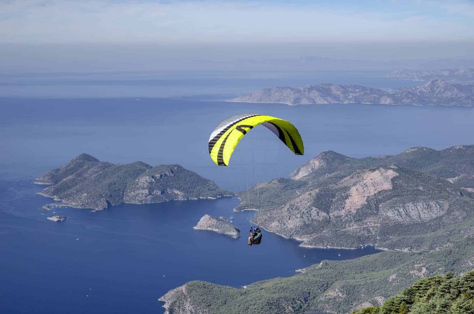 Paraglider fly over the coastline from the top of Babadag
