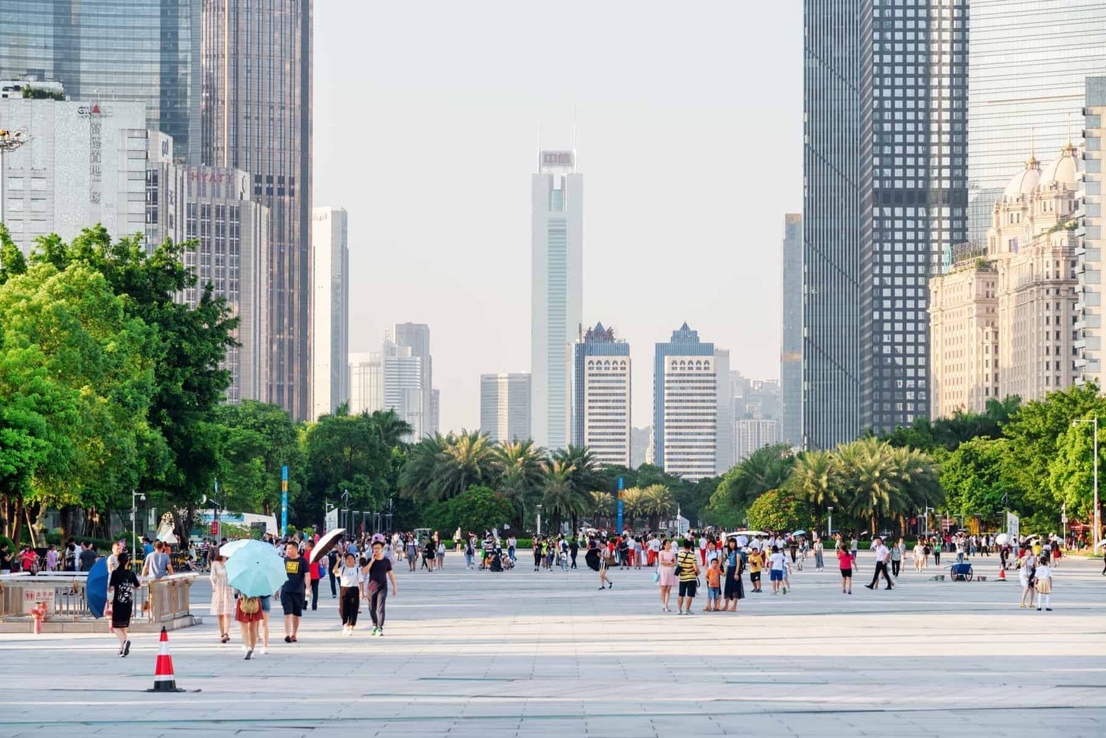 Guangzhou, China - September 16, 2017: Asian tourists walking in a scenic city park among modern buildings in the Tianhe District of the Zhujiang New Town. Guangzhou is a popular tourist destination.
