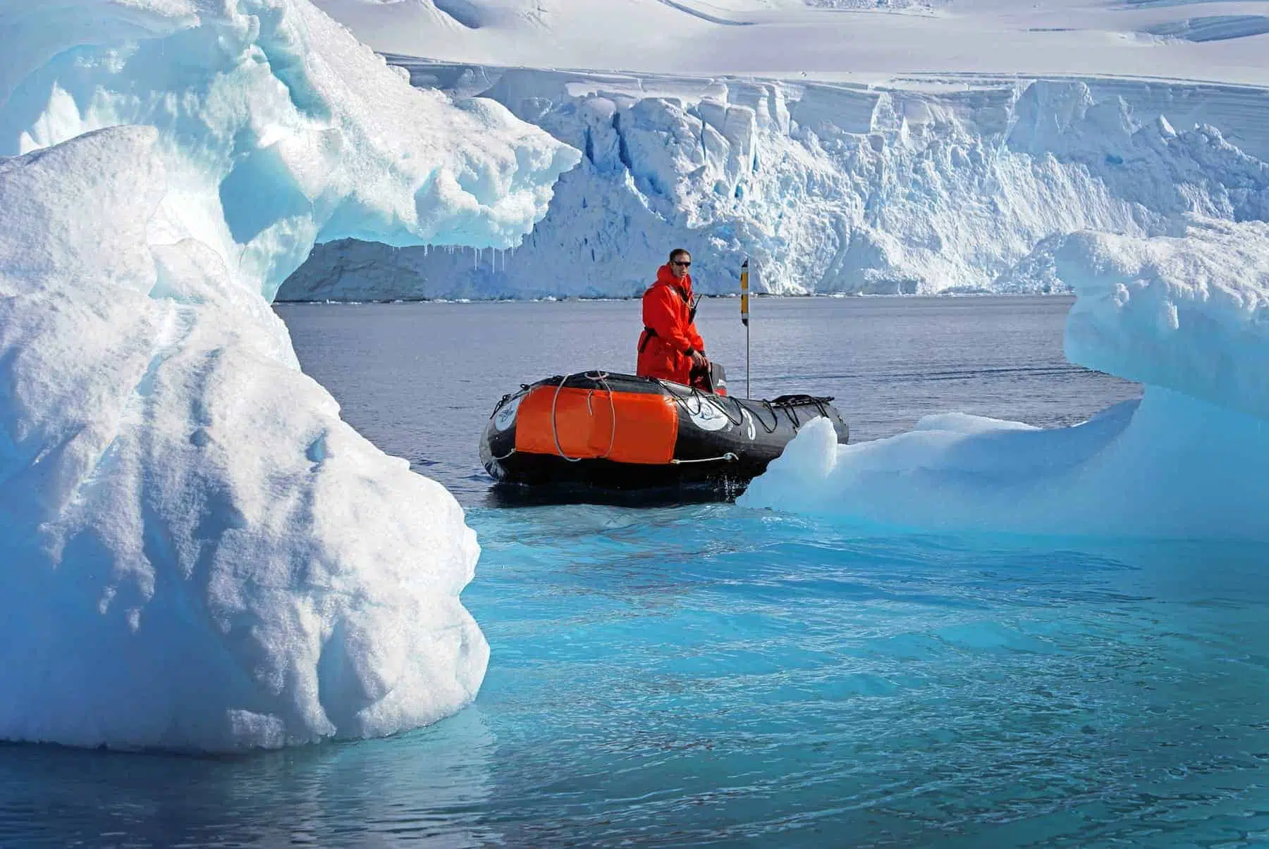 Man sightseeing on small raft amongst beautiful Icebergs at Antarctica.