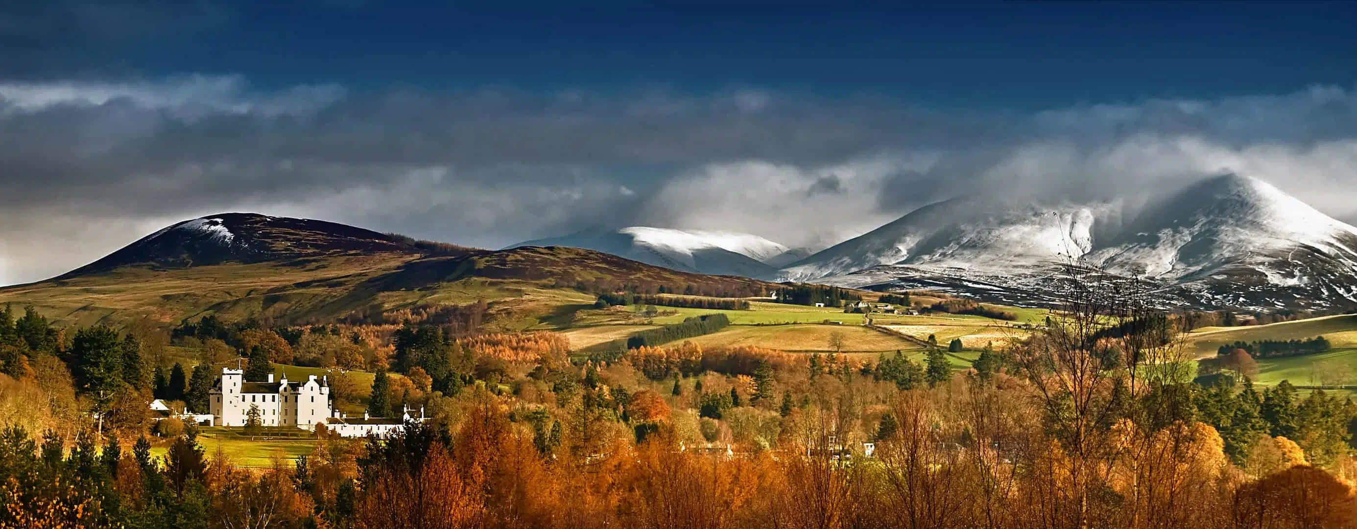 Blair Castle in Perthshire Scotland, an Autumnal scene with snow-capped mountains.
