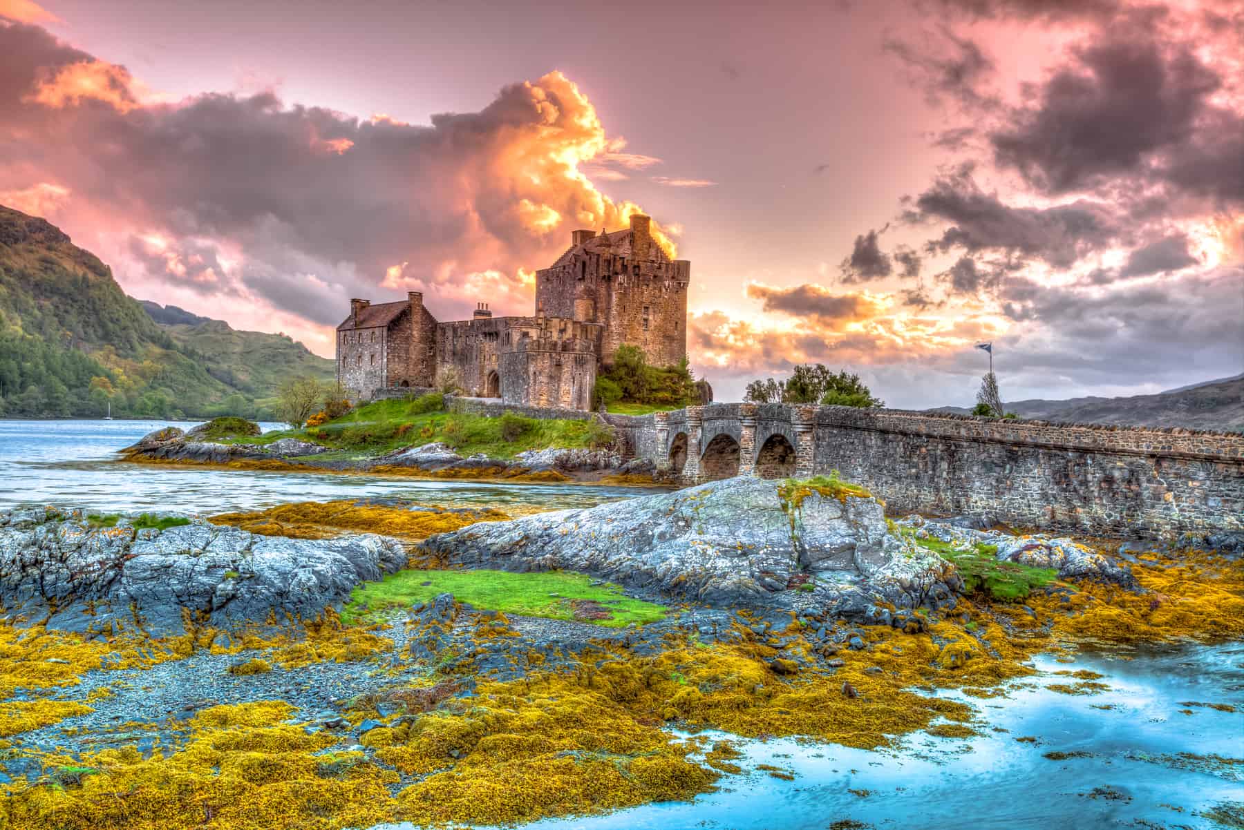 Ancient Scottish castle overlooking loch at sunset.