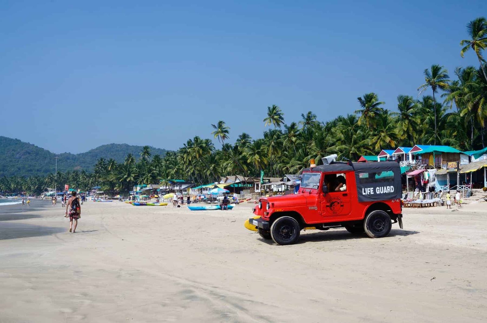GOA,PALOLEM BEACH,INDIA - DECEMBER 4:unidentified life guard red car watching for tourists enjoying beautiful Palolem beach on December 4,2013 in Goa,Palolem beach,India.Arabian sea has very strong and dangerous sea currebts