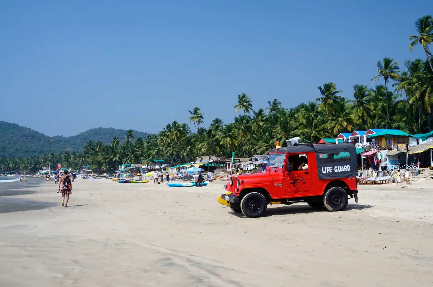 GOA,PALOLEM BEACH,INDIA - DECEMBER 4:unidentified life guard red car watching for tourists enjoying beautiful Palolem beach on December 4,2013 in Goa,Palolem beach,India.Arabian sea has very strong and dangerous sea currebts