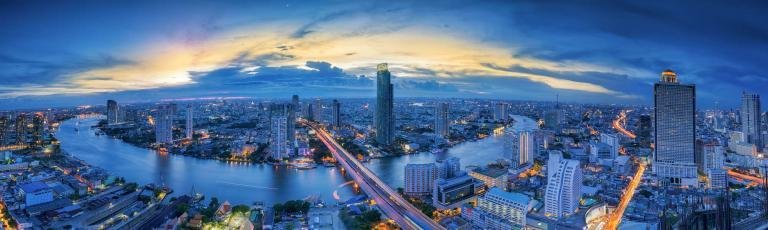 Bangkok skyline at sunset with Chao Phraya River and modern skyscrapers, urban cityscape view for travel and vacation destinations.