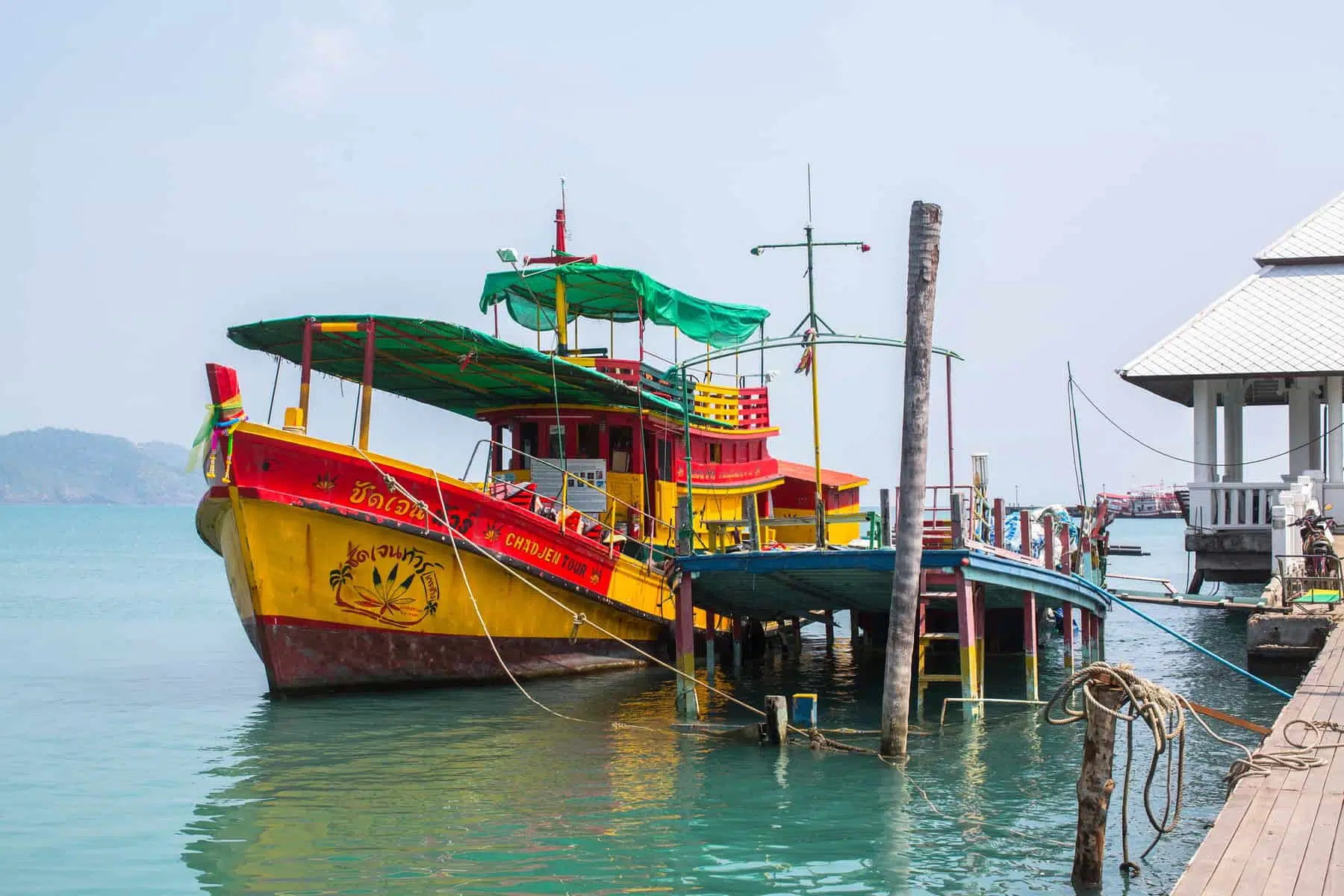 Lush green island with white sandy beach and turquoise waters, popular vacation destination in Thailand.