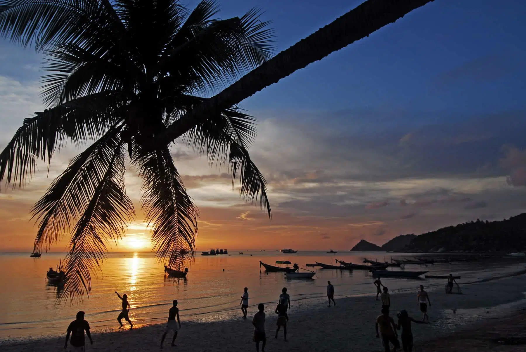 Lush green island with white sandy beach and turquoise waters, popular vacation destination in Thailand.