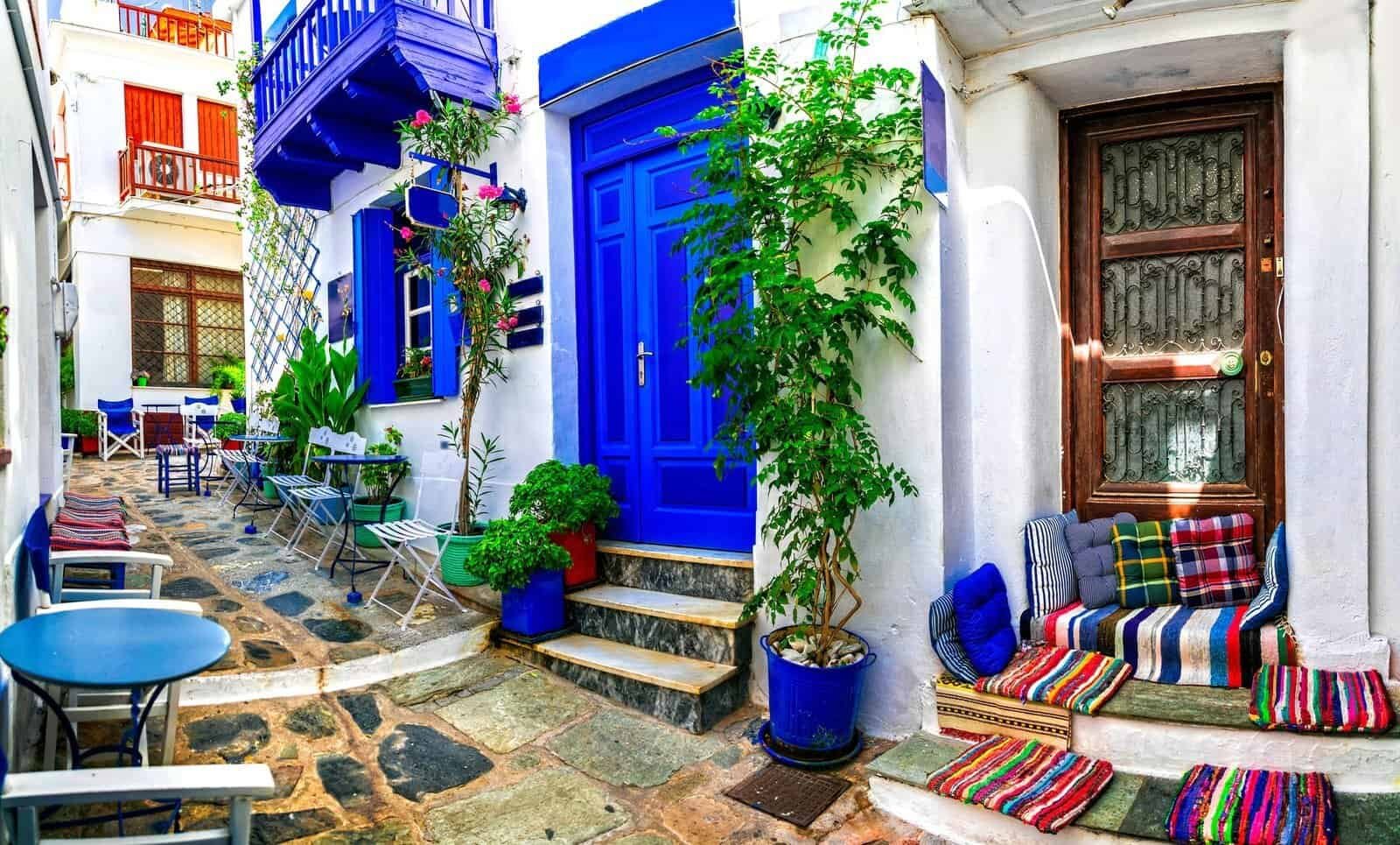 Colorful cobblestone street with outdoor seating and vibrant storefronts in a charming European village.