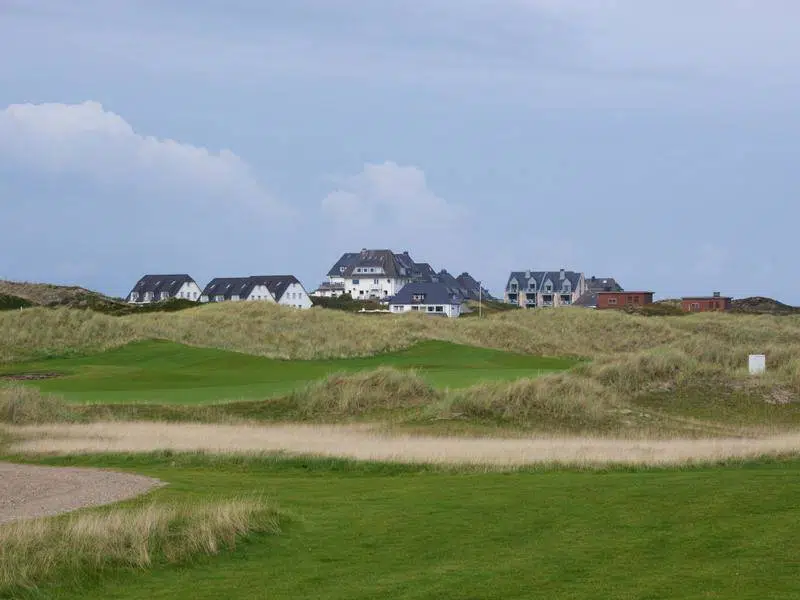 Lush golf course with well-maintained greens and scenic trees, ideal for a relaxing vacation golf outing.