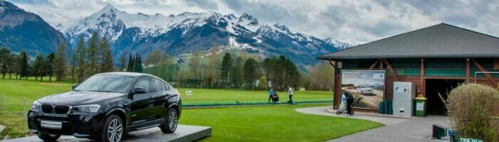 Golf club Kaprun Zell am See. Black BMW on green of golf course with Alps in background