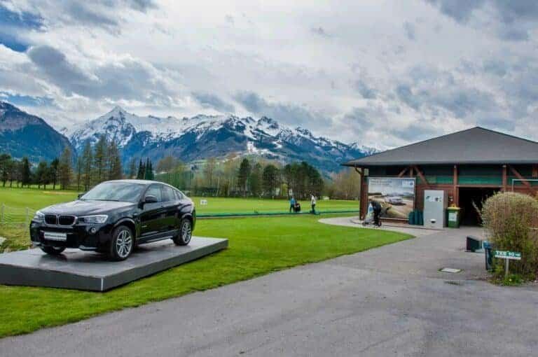 Golf club Kaprun Zell am See. Black BMW on green of golf course with Alps in background