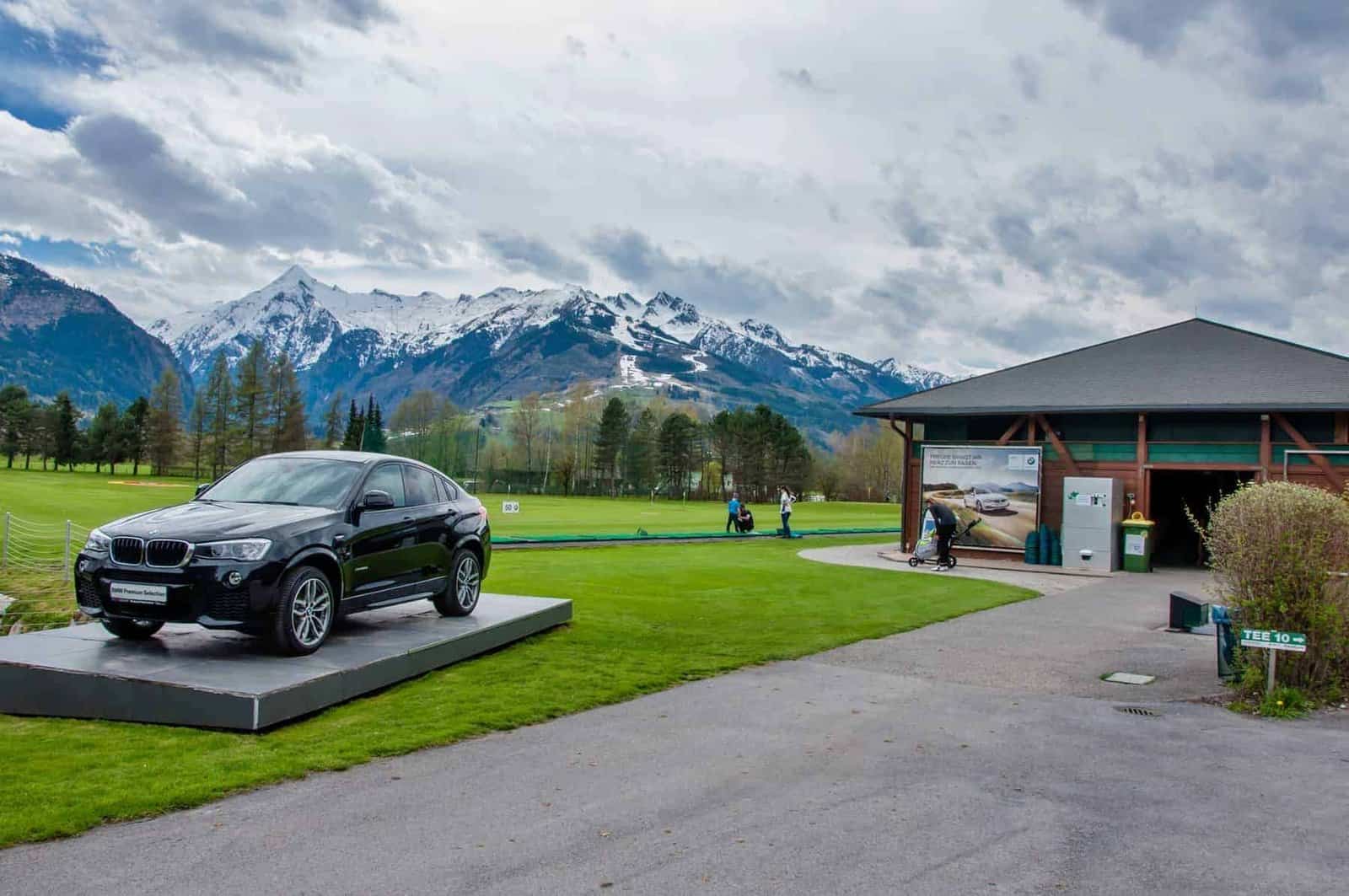 Golf club Kaprun Zell am See. Black BMW on green of golf course with Alps in background