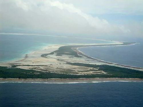 Aerial view of a tropical island with white sandy beaches and blue ocean waters.