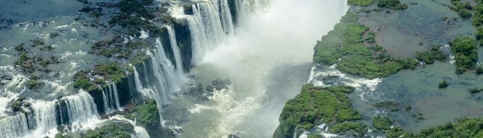 Vivid aerial view of Victoria Falls showcasing cascading waterfalls and lush surrounding greenery at the border of Zimbabwe and Zambia.
