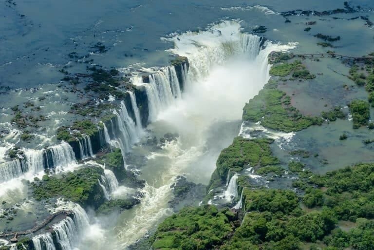 Vivid aerial view of Victoria Falls showcasing cascading waterfalls and lush surrounding greenery at the border of Zimbabwe and Zambia.