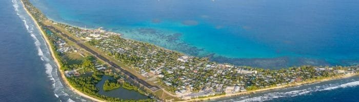 Aerial view of a tropical island with clear blue ocean waters and lush greenery.