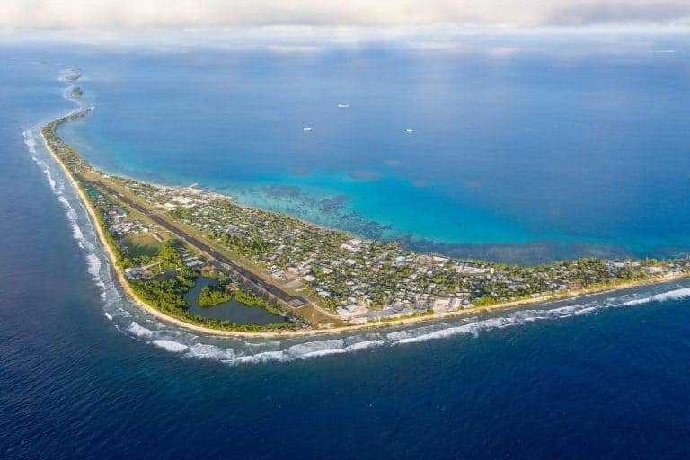 Aerial view of a tropical island with clear blue ocean waters and lush greenery.