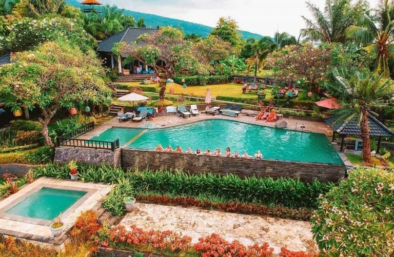 Tranquil tropical resort with infinity pool surrounded by lush greenery and scenic mountain views.