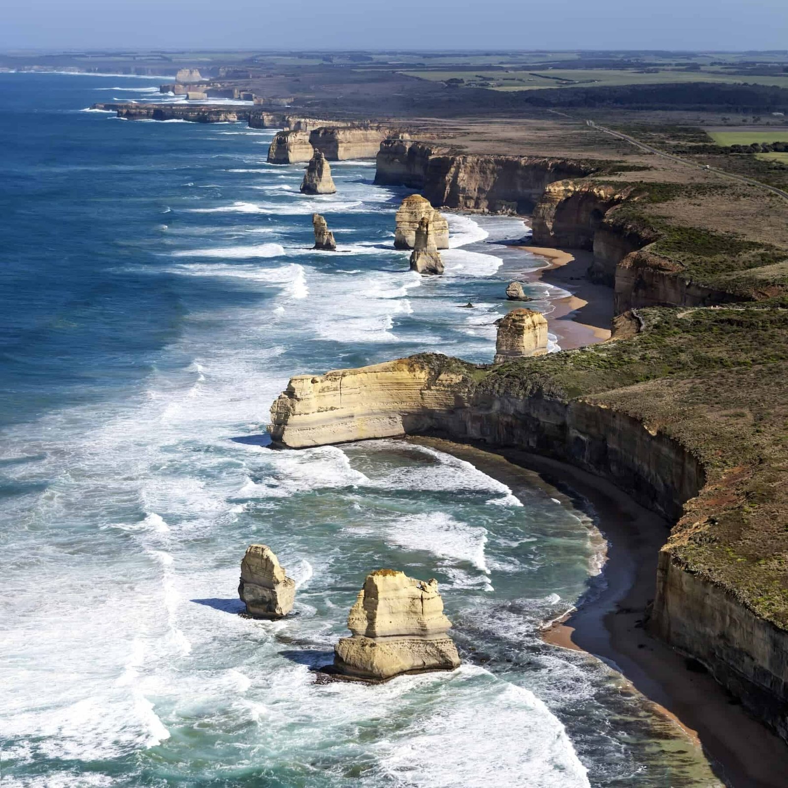 Jagged rock formations along a rugged coastline with high cliffs and crashing waves.