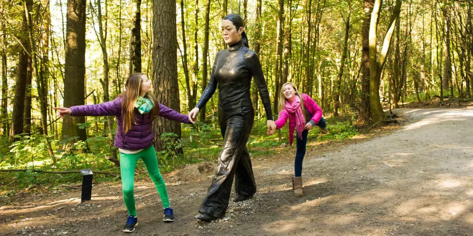 Mysterious woman sculpture with children in forest, outdoor art installation for nature-themed travel attractions.