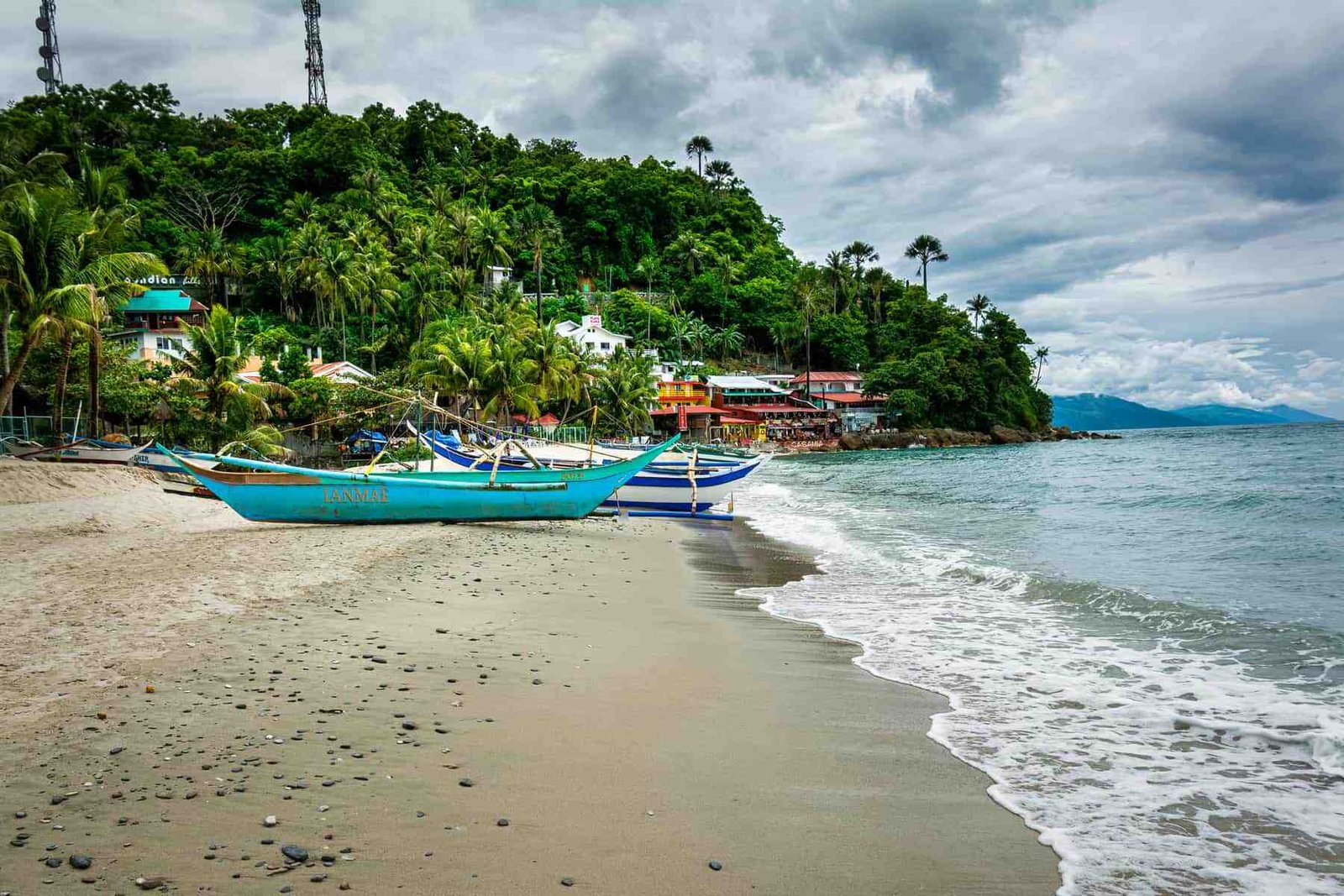 Vibrant tropical island cove with clear blue water and lush green mountains in the background.