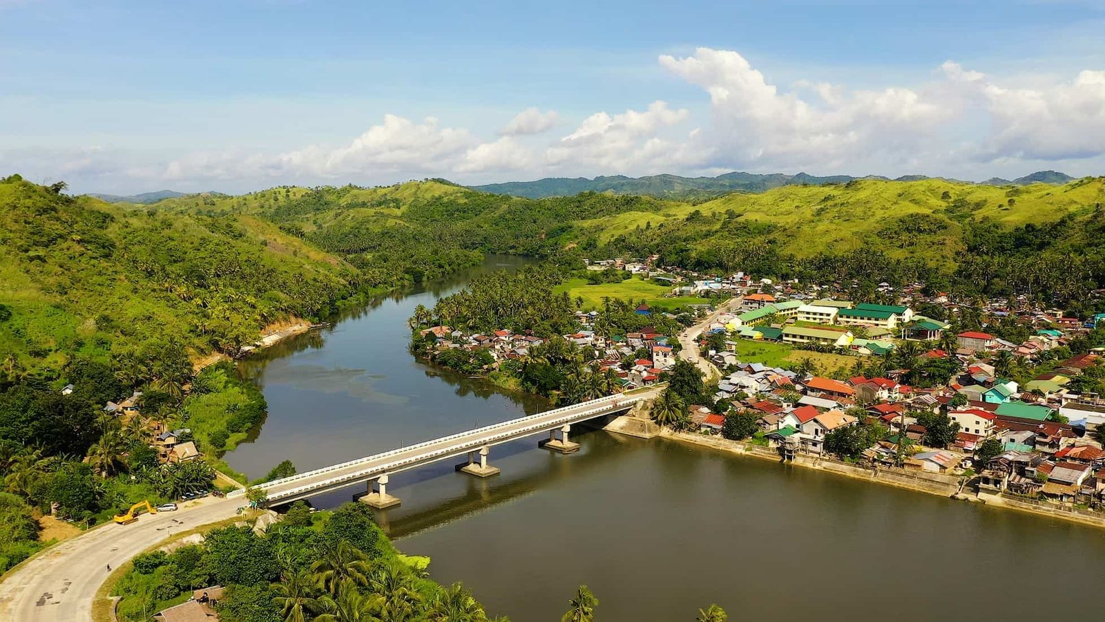 Vibrant tropical island cove with clear blue water and lush green mountains in the background.