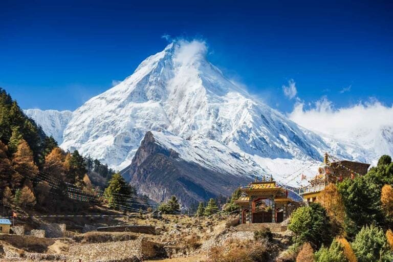 Snow-capped Himalayan mountain with colorful Tibetan monastery in the foreground, vibrant travel destination.