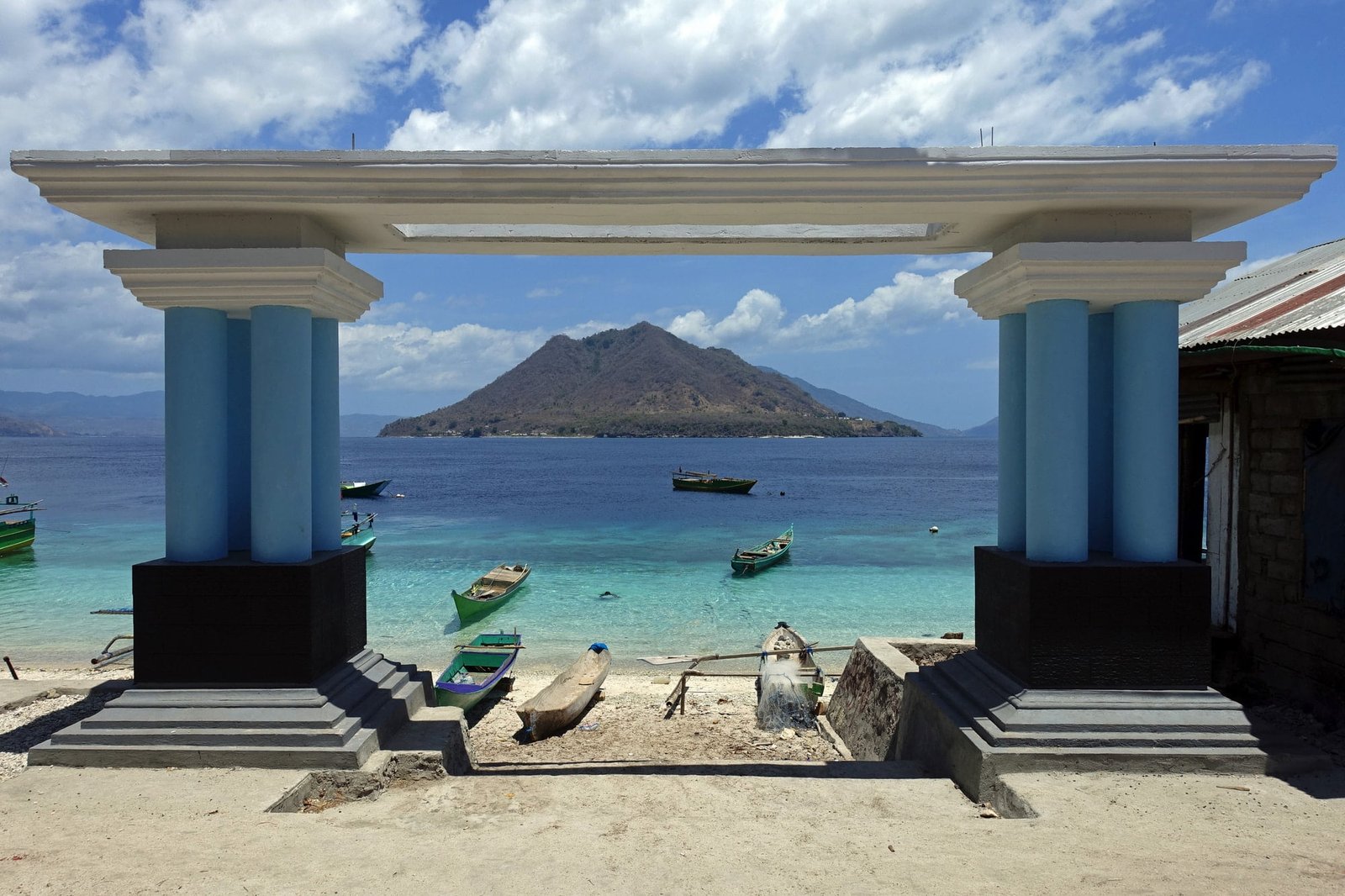 Secluded beach resort island with overwater bungalows surrounded by lush tropical forest and clear blue waters.