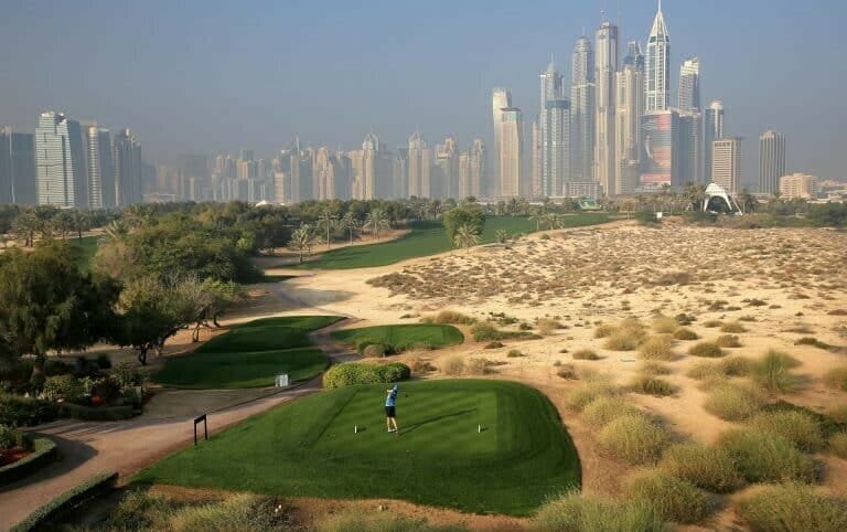 Lush golf course with city skyline and modern skyscrapers in the background, sunny day at Dubai golf course.