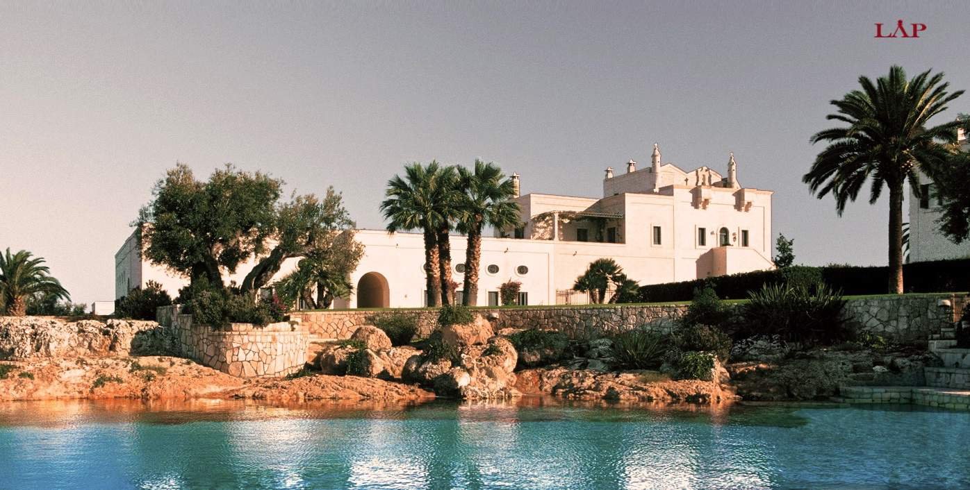 Luxurious tropical resort with illuminated main building at dusk, reflecting in the water.