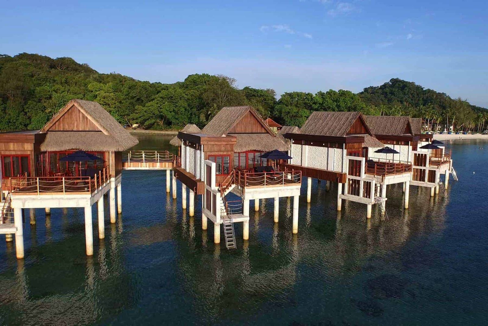 Overwater bungalows with thatched roofs and private decks on a tropical island, perfect for luxury vacations and relaxation.