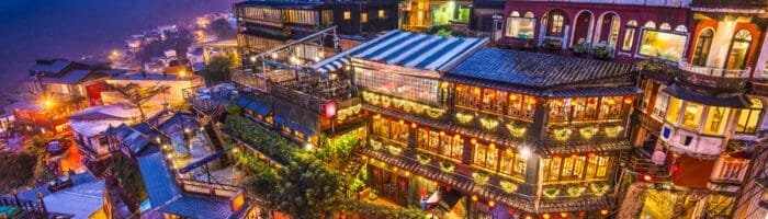 Colorful hillside resort with illuminated buildings at night, surrounded by mountains, perfect for vacation travel in Taiwan.