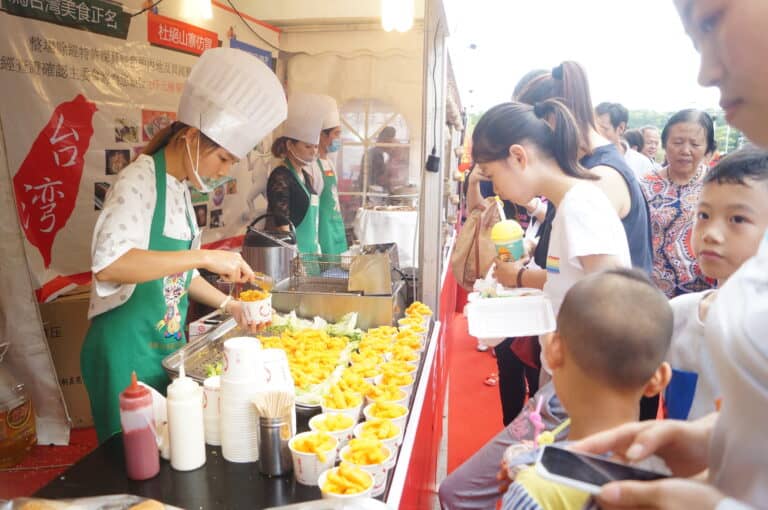Fresh food stall at a cultural festival with chefs serving traditional dishes to excited visitors.