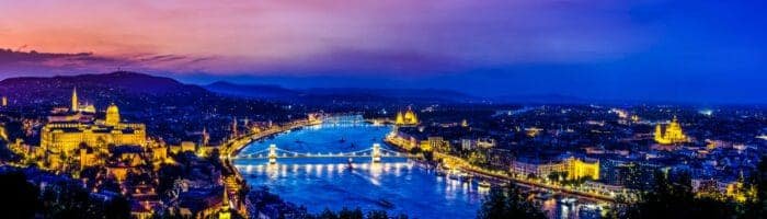Budapest city skyline at dusk with illuminated Chain Bridge over Danube River and historic landmarks.