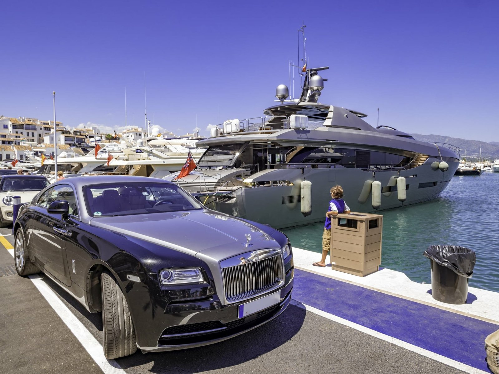 Malaga, Spain, Circa August 2018. Rolls-Royce car next to a huge yacht in Puerto Banus, a luxury harbour and marina in Marbella popular for the jetset