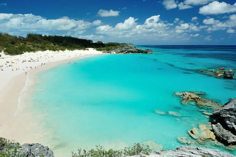 Turquoise beach with white sand and rocky cliffs on a sunny day.