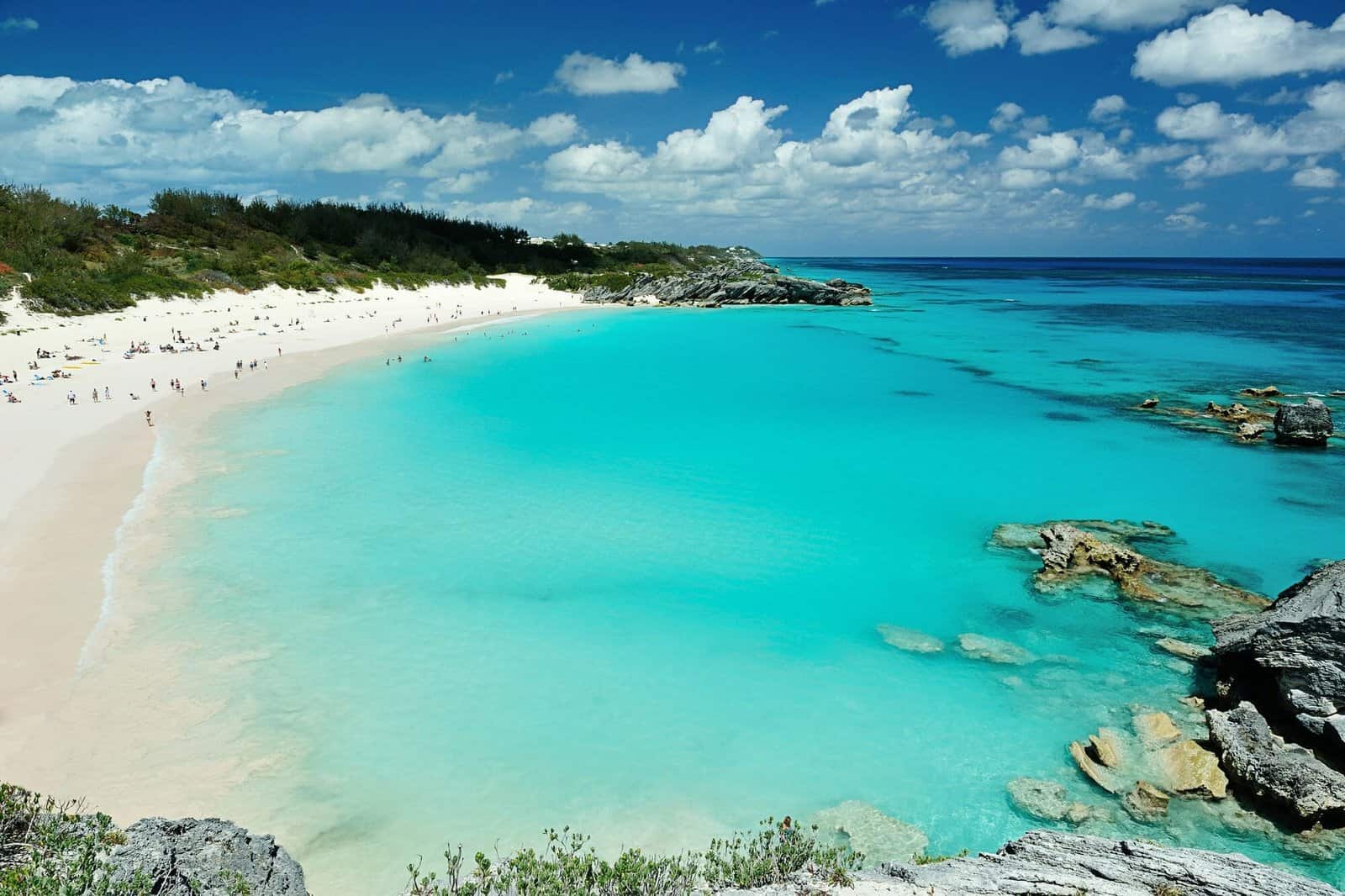 Turquoise beach with white sand and rocky cliffs on a sunny day.