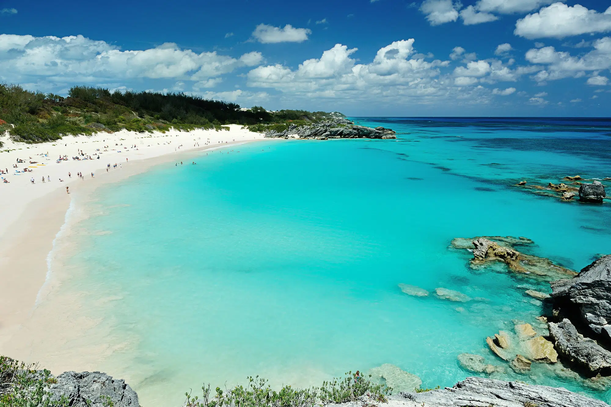 Turquoise beach with white sand and rocky cliffs on a sunny day.