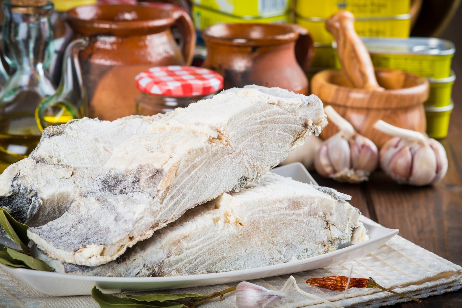 Salted cod cut with ingredients and utensils on the table of the kitchen for cooking