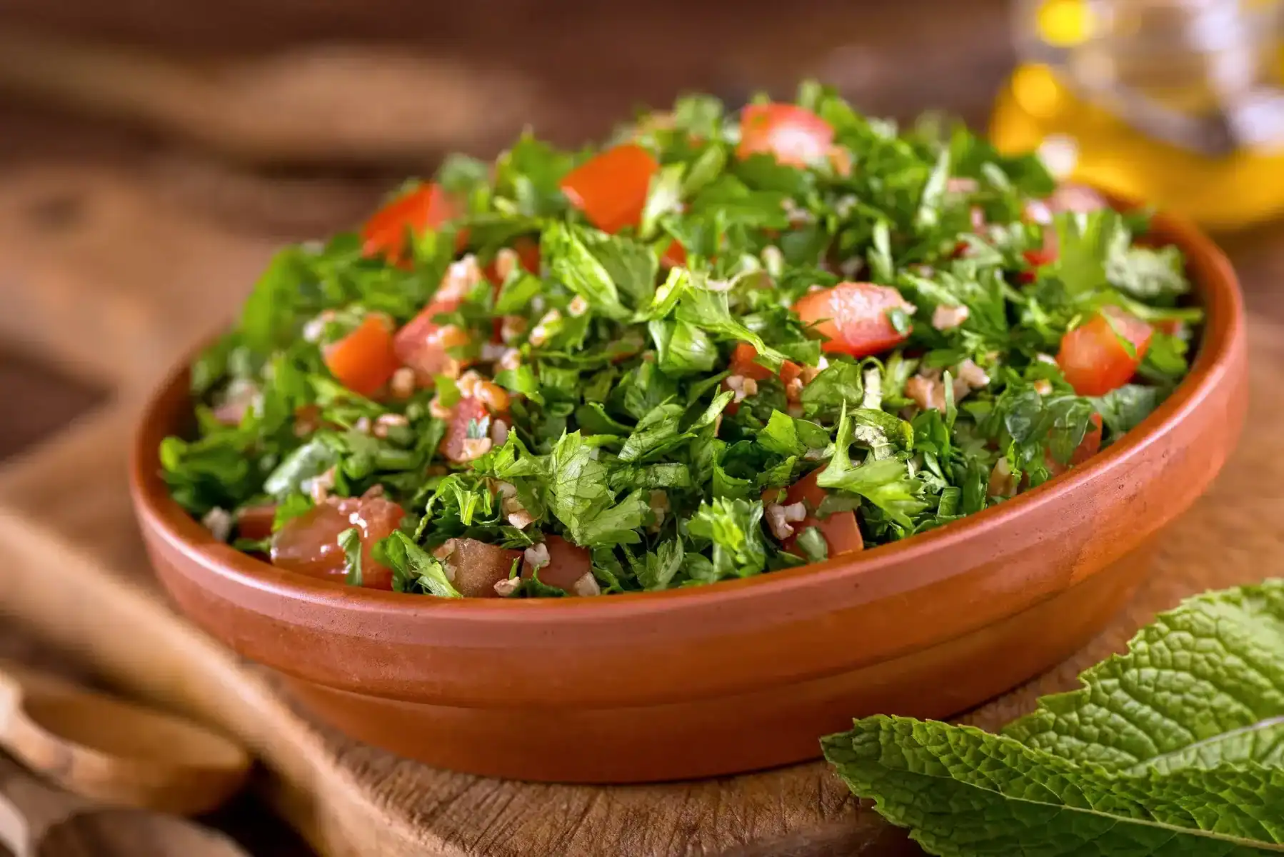 A bowl of delicious fresh tabouli with parsley, mint, tomato, onion, olive oil, lemon juice, and bulgar wheat.