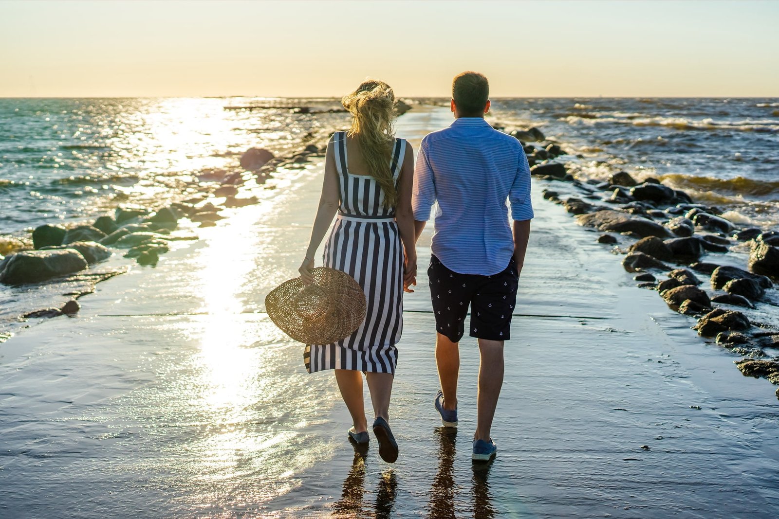 Back view of couple in love walking on seashore during sunset in Riga, Latvia