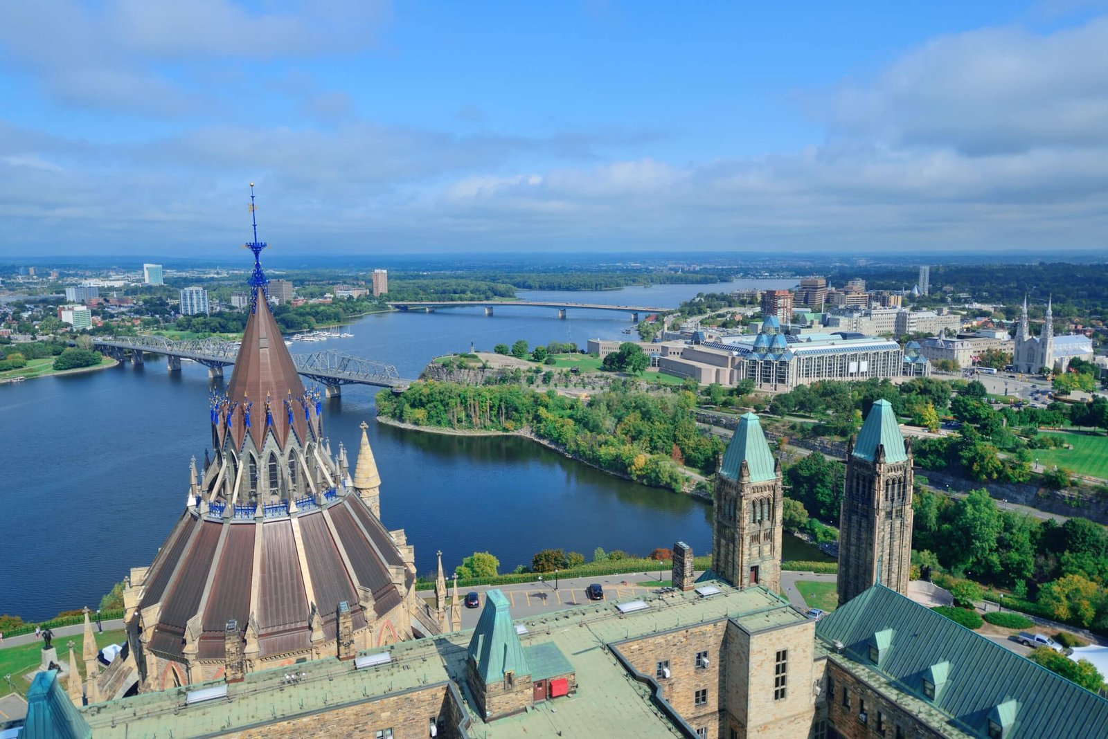 Ottawa cityscape in the day over river with historical architecture.