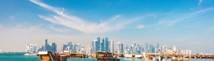 Waterfront in Doha Qatar with traditional wooden small ships known as dhow and city skyline
