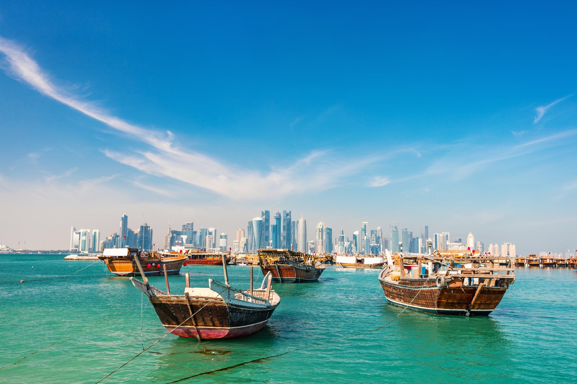 Waterfront in Doha Qatar with traditional wooden small ships known as dhow and city skyline