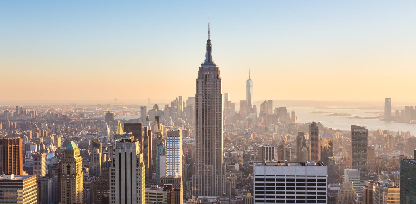 Manhattan downtown skyline with illuminated Empire State Building and skyscrapers at sunset seen from Top of the Rock observation deck