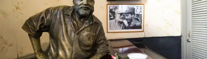 Glass of Daiquiri cocktail and statue of American writer Ernest Hemingway in the bar El Floridita in Havanna