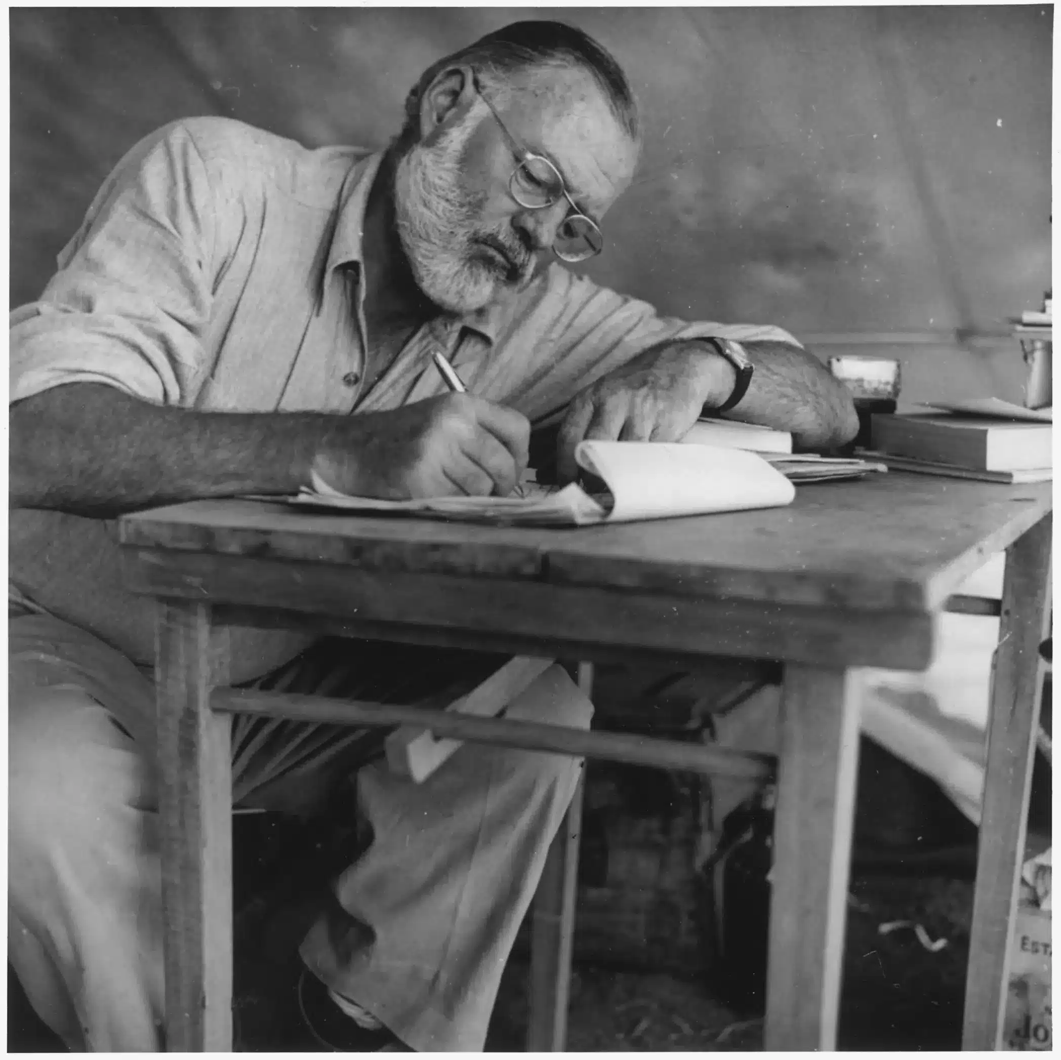 Ernest_Hemingway_Writing_at_Campsite_in_Kenya