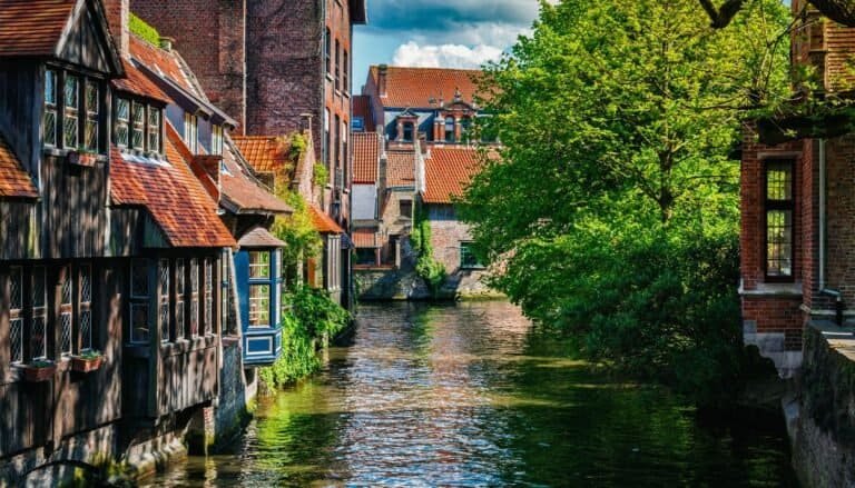 Colorful European canal scene with traditional houses and lush greenery in spring.