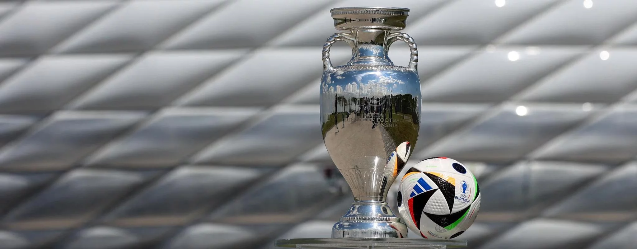 Shiny European Championship trophy with Euro 2020 soccer ball on metallic background.
