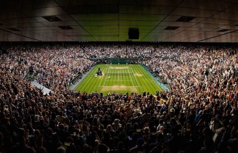 Stadium packed with spectators during tennis match.
