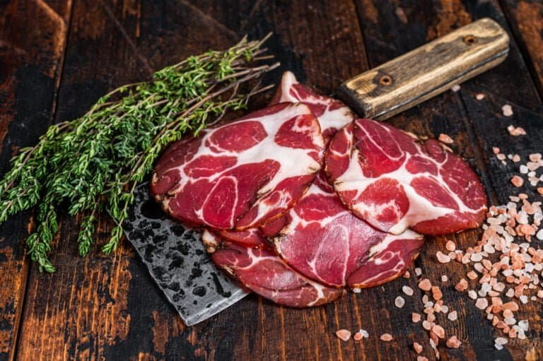 Coppa, Capocollo, Capicollo Cured ham on meat cleaver. Dark wooden background. Top view.